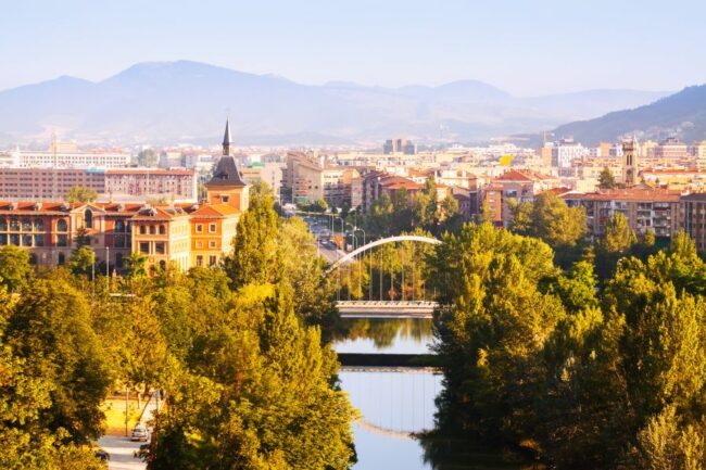 Vista aérea de Pamplona con el puento sobre el río y los edificios al fondo.