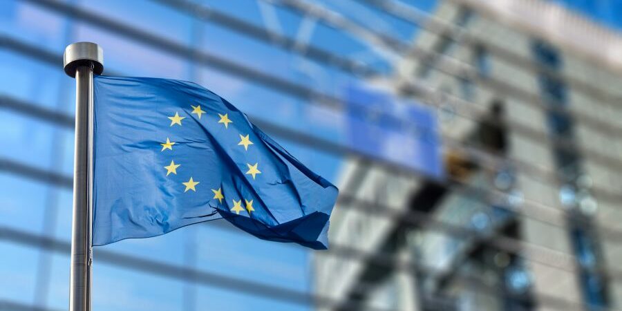 Bandera de la Unión Europea ondeando con el edificio del parlamento Europeo al fondo en Bruselas.
